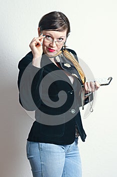 Beautiful sexy business woman with glasses looking at the camera provocatively dressed in black jacket and jeans, holding mobile