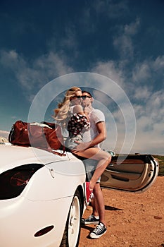 Beautiful couple in casual clothes posing beside auto