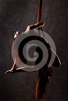 Beautiful dancer on aerial silk, graceful contortion, acrobat performs a trick on a ribbons