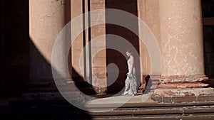 Beautiful sexy elegant lady walks near the old columns of the old mansion.