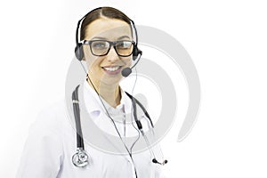 Beautiful sexy female doctor in white coat, headset looks at camera with smile