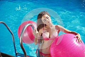Beautiful female model with pilates fitballs posing in swim
