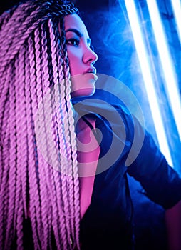 Beautiful sexy girl with long dreadlocks posing in neon light