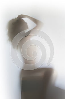 Beautiful and sexy long hair woman sits and poses behind a bathroom curtain.