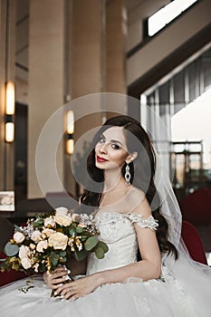 Beautiful and sexy model woman in the fashionable wedding dress holds a bouquet of fresh flowers