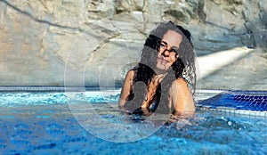 Beautiful sexy portrait of mature woman with dark curly hair relaxes contend happy in holidays summer sun in the blue spa wellness