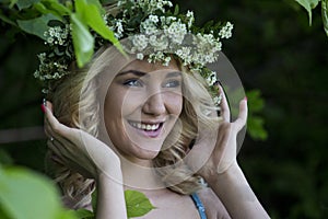 Beautiful smiling girl with a wreath on his head in the spring park