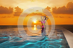 Beautiful sexy tanned woman bikini model on Maldives at sunset. Young glamour girl in swimsuit in pool. Perfect body bikini model