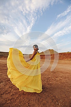 Beautiful sexy woman with dark hair in elegant dress and accessories posing in desert