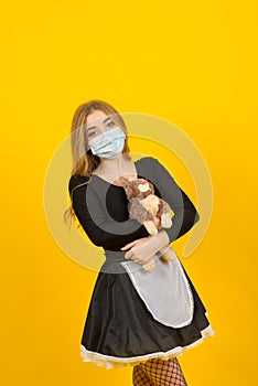 Beautiful sexy woman in maid clothes posing with rabbit toy in covid protective mask