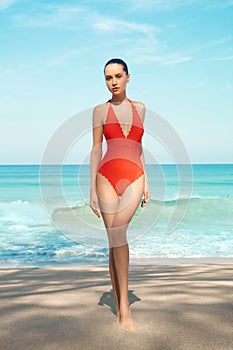 Beautiful sexy woman in red swimwear on the beach