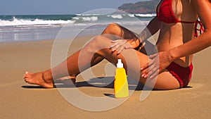 Beautiful and sexy young shugaring woman is applying sunscreen on the body on the sea. ultraviolet rays oil for tanning