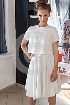 Beautiful young woman in beautiful fashionable white dress in the studio posing for the camera fashion shoot for the clothing