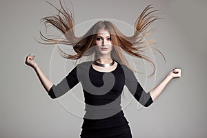 Beautiful young woman in a black dress with bright makeup throws red hair