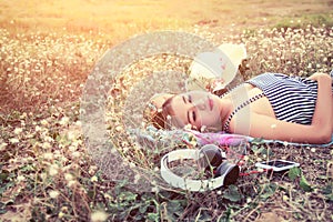 Beautiful young woman lying nearing headphone in the flower