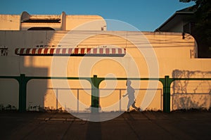 Beautiful shadow of women runner on cream wall background. Sunset light shines down around the wall and house. Running isolate