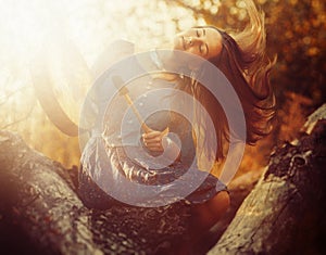 Beautiful shamanic girl playing on shaman frame drum in the nature.