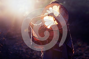 Beautiful shamanic girl playing on shaman frame drum in the nature