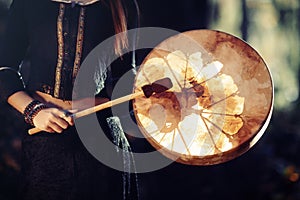 Beautiful shamanic girl playing on shaman frame drum in the nature