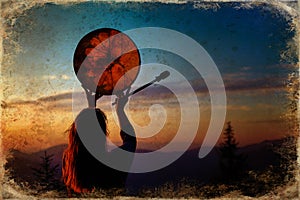 Beautiful shamanic girl playing on shaman frame drum in the nature, old photo effect.