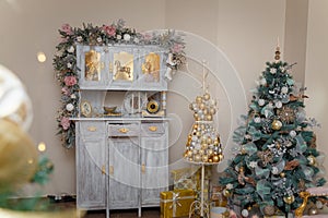 Beautiful shebby chic cupboard decorated with artificial snowy fir branches, icy roses, rocking horse toy, golden Christmas