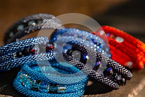 Beautiful, shiny, colorful bracelet set with large beadwork beads. On a wooden bench in the park. Jewelry on hand