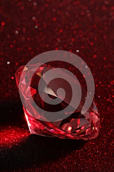 Beautiful shiny diamond on red glitter background, closeup