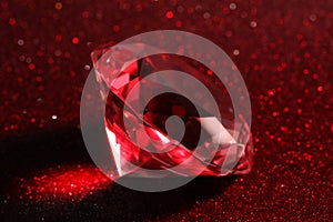 Beautiful shiny diamond on red glitter background, closeup