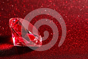 Beautiful shiny diamond on red glitter background, closeup. Space for text