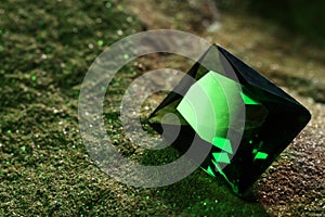Beautiful shiny green gemstone on stone, closeup. Space for text