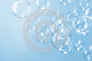 Beautiful shiny transparent soap bubbles float on blue background.