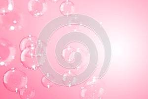 Beautiful shiny transparent soap bubbles floating on a pink background