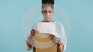 Beautiful shocked casual african american girl opening envelope with exams results on camera over colorful background