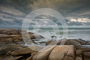 Beautiful shore and rain clouds with rocks on the beach