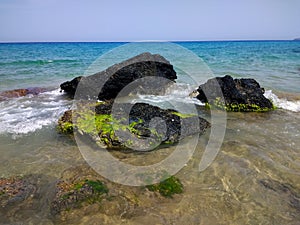 Beautiful shot of black rocks lying next to the beach in Ibiza, Spain photo