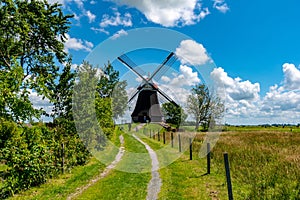 Beautiful shot of a black windmill in a field in the countryside with a bright cloudy sky background