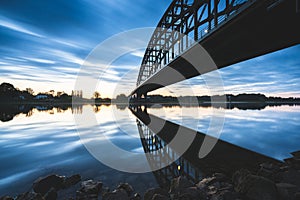 Beautiful shot of a bridge over a reflective lake during the sunset