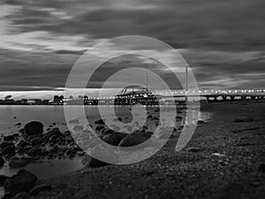 Beautiful shot of the bridge over the water under a cloudy sky in black and white
