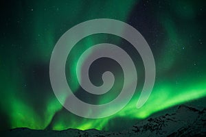 Beautiful shot of bright green aurora northern lights over mountains in Norway