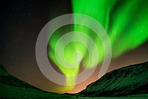 Beautiful shot of bright green aurora northern lights over mountains in Norway