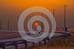 Beautiful shot of a car on the road, sun and street lights during an orange sunset
