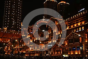 Beautiful shot of Chinese traditional houses illuminated at night against skyscrapers