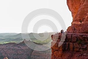 Beautiful shot of a couple sitting on the Cathedral Rock at sunset in Sedona, Arizona, United States