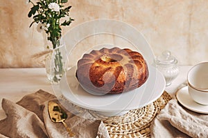 Beautiful shot of a delicious ring cake put on a white plate and a white flower near it