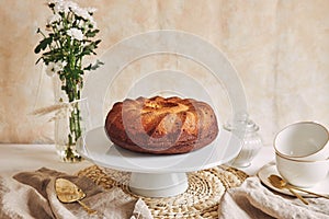 Beautiful shot of a delicious ring cake put on a white plate and a white flower near it