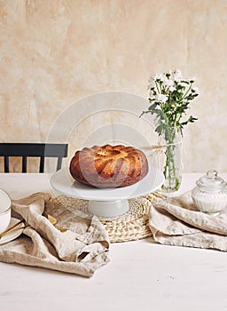 Beautiful shot of a delicious ring cake put on a white plate and a white flower near it