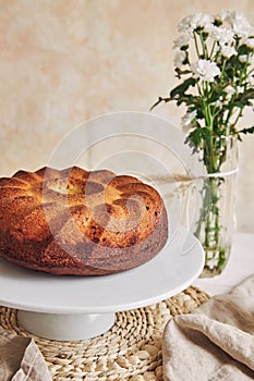 Beautiful shot of a delicious ring cake put on a white plate and a white flower near it