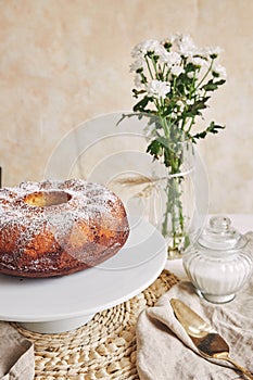 Beautiful shot of a delicious ring cake put on a white plate and a white flower near it