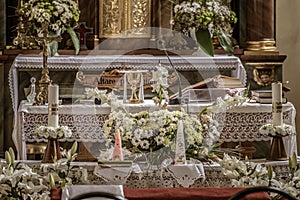 Beautiful shot of flowers, candles, and chalice in the white altar of a church