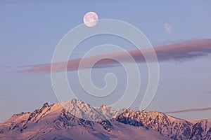 Beautiful shot of the full moon over the snowy Saile mountain